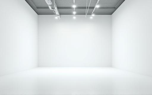 Vue large d'un grand espace de studio vide avec un sol clair et des murs blancs